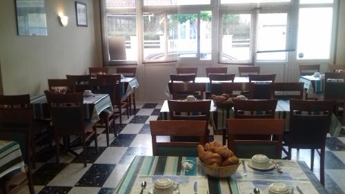 a dining room with tables and chairs and windows at Hotel le Bon Soleil in Les Sables-d'Olonne