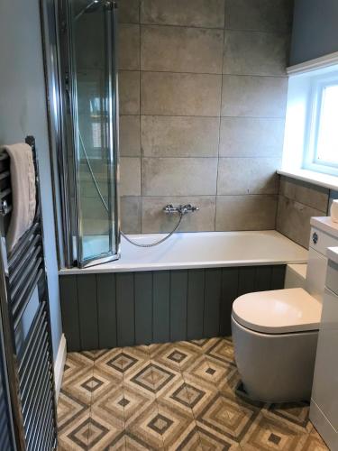 a bathroom with a shower and a toilet and a tub at The White Horse Hotel in Leiston