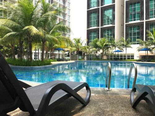 a chair next to a swimming pool with palm trees at Fabulous Mutiara Ville Cyberjaya in Cyberjaya