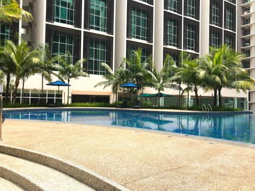 a swimming pool in front of a building with palm trees at Goldenstay Mutiara Ville Cyberjaya in Cyberjaya