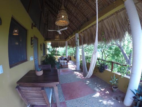 a porch of a house with a table and swings at Casa Aditi in Mazunte