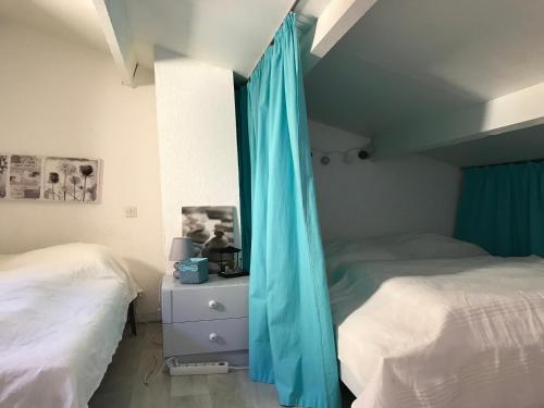- 2 lits dans une chambre avec des rideaux bleus dans l'établissement Port leucate T2 bis wifi les Sables 3, à Port-Leucate