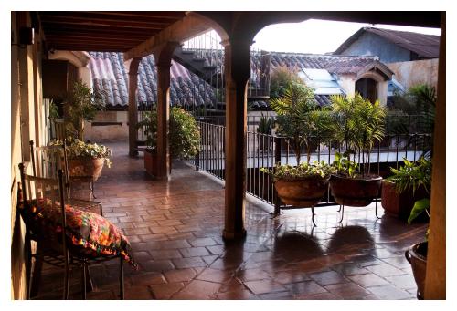 an outdoor patio with chairs and potted plants at Meson de Maria in Antigua Guatemala