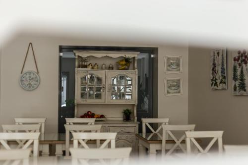 a dining room with white chairs and a mirror at Ester Guest House in Chaves