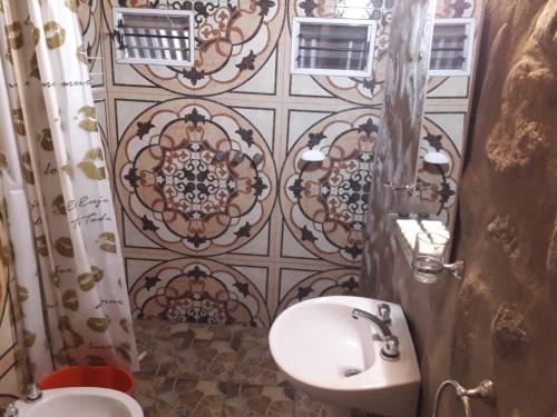 a bathroom with a sink and a toilet and a tile wall at Cabañas Laukan in San Agustín de Valle Fértil