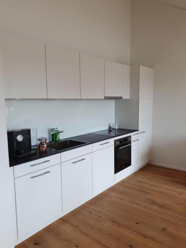a white kitchen with white cabinets and a wooden floor at Wohnstation in Subingen
