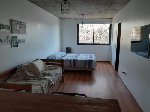 Zimmer mit 2 Betten, einem Sofa und einem Fenster in der Unterkunft Depto calle 20 y 37 - monoambiente, muy bonito y luminoso! in La Plata