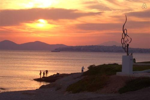 a group of people standing on a beach at sunset at SEASIDE SUNSET WALKS in Athens