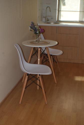 a table with three chairs and a vase of flowers at thomas guest house in Tbilisi City