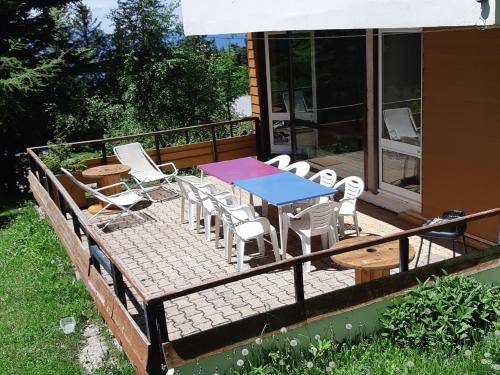 a deck with a blue table and white chairs at Chamrousse 1750 - Le Taillefer - Appartement classé 3 étoiles in Chamrousse