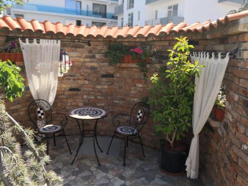 a patio with two chairs and a table and a brick wall at Vila Kataleya Mamaia Nord in Mamaia Nord
