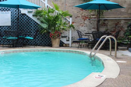 a swimming pool with an umbrella and tables and chairs at Hotel St. Pierre French Quarter in New Orleans