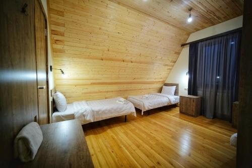 a room with two beds in a wooden room at Hotel TWINS Achkhoti in Stepantsminda