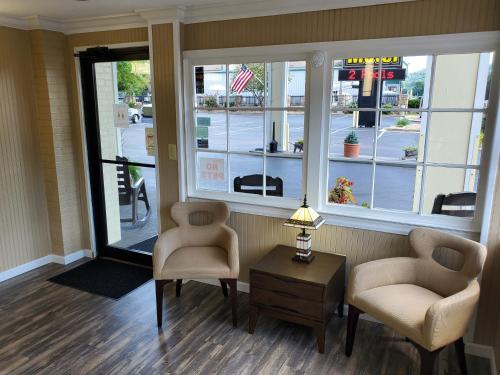 a waiting room with two chairs and a table and windows at Colonial House Motel in Pigeon Forge