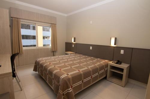 a hotel room with a bed and a window at A Furninha Hotel in Torres
