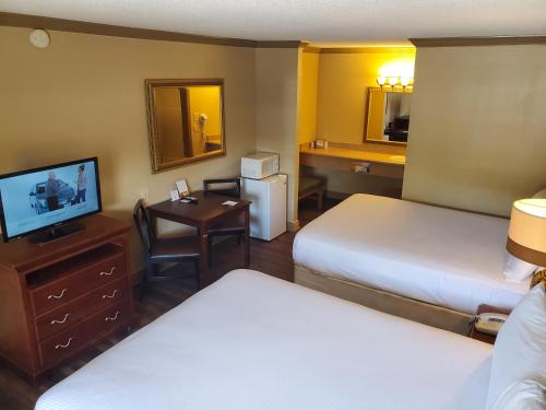 a hotel room with two beds and a desk and a television at Colonial House Motel in Pigeon Forge