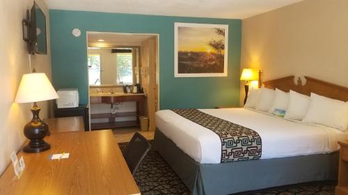 a hotel room with a bed and a desk and a table at Days Inn by Wyndham Attalla in Attalla