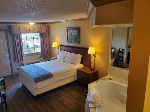 a hotel room with a bed and a bath tub at Colonial House Motel in Pigeon Forge
