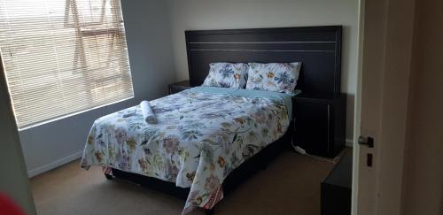 a bedroom with a bed with a large black headboard at Neat Haven Self Catering in Grahamstown