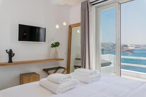 a bedroom with a bed with a view of the ocean at Obsession Mykonos in Agios Stefanos