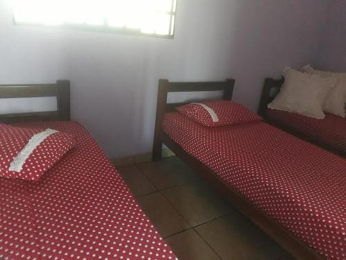 two beds in a room with red and white sheets at Pousada Fora de Rota in Colinas Do Sul