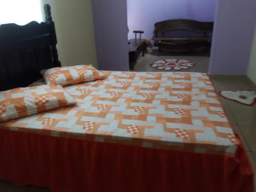 a bed with an orange and white quilt on it at Pousada Fora de Rota in Colinas Do Sul