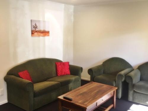 a living room with two chairs and a coffee table at Woodlands Motels And Apartments in Dunedin