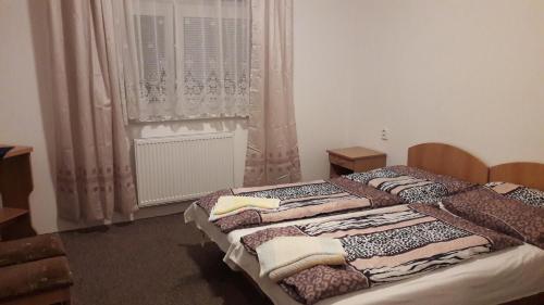 een slaapkamer met 2 bedden en een raam met gordijnen bij PENZION EUROPA Diakovce in Diakovce
