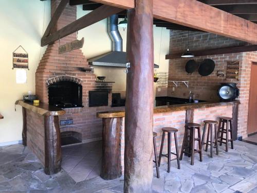 a kitchen with a brick fireplace and bar with stools at Pousada Circuito das Aguas in Jaguariúna