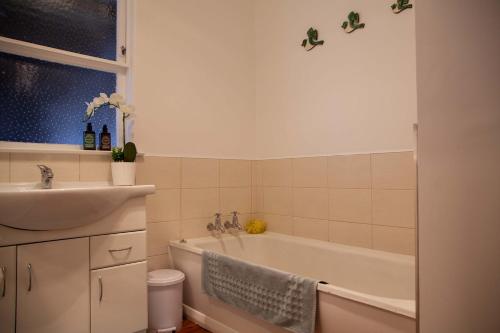 a bathroom with a sink and a bath tub at Languor B&B in Carterton