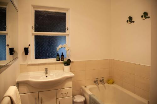a bathroom with a sink and a bath tub and a sink at Languor B&B in Carterton