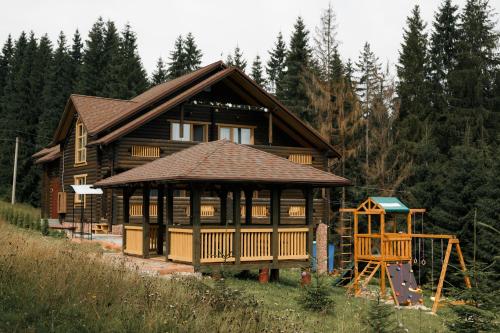 a large wooden house with a playground in front of it at GUTSULWOOD in Yablunytsya