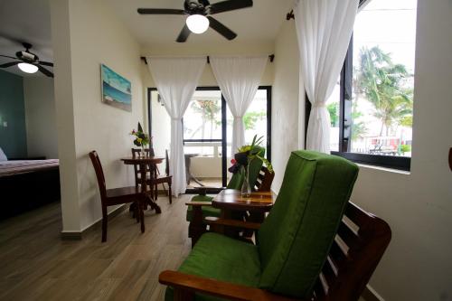 a living room with a green chair and a table at Jan's Hotel in Caye Caulker