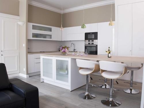 una cocina con armarios blancos y taburetes de barra blanca en Sasha bel appartement renove centre ville Beaune, en Beaune