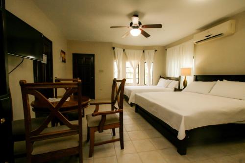 a bedroom with two beds and a ceiling fan at Jan's Hotel in Caye Caulker