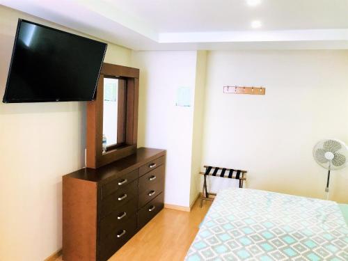 a bedroom with a dresser with a flat screen tv on the wall at Hotel & Suites Victoria in San Luis Potosí