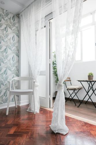 a room with white curtains and a wooden floor at 4U Lisbon Suites & Guesthouse VII Airport in Lisbon