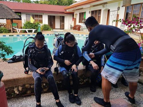 un groupe de personnes assises près d'une piscine qui regardent leurs téléphones portables dans l'établissement Eve's Kiosk Dive Resort, à Moalboal