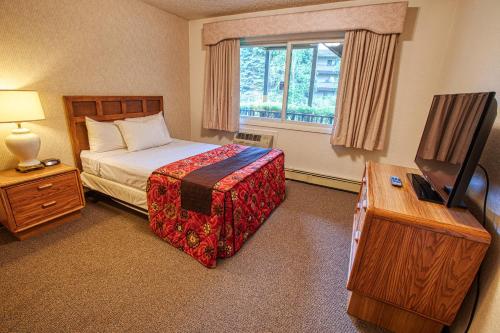 um quarto de hotel com uma cama e uma televisão em Wedgewood Resort em Fairbanks