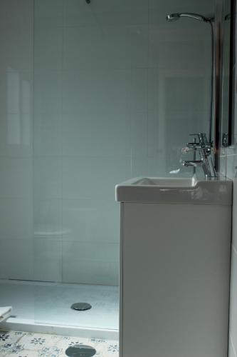 a white bathroom with a sink and a shower at Casa Devesas in Vila Nova de Gaia