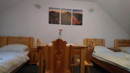 a room with three beds and a table and chairs at POKOJE GOŚCINNE BETKA in Murzasichle
