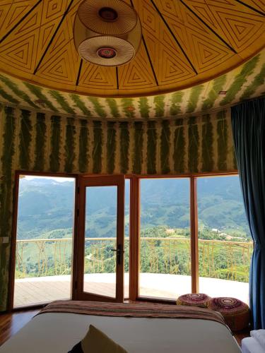 a bedroom with a large window with a mountain view at Sapa Clay House - Mountain Retreat in Sa Pa