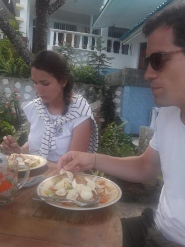 a man and woman sitting at a table with a plate of food at Bintang Bungalow Tour & Travel in Kelimutu