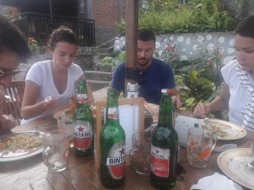 a group of people sitting at a table with beer bottles at Bintang Bungalow Tour & Travel in Kelimutu