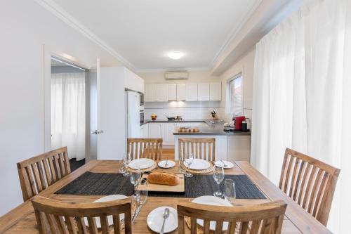 a dining room with a table and chairs and a kitchen at Kimberley Gardens Hotel, Serviced Apartments and Serviced Townhouses in Melbourne