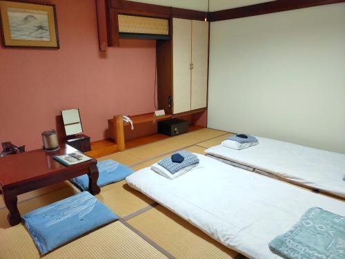 a room with two beds and a desk and a table at Tsukefuneya in Joetsu