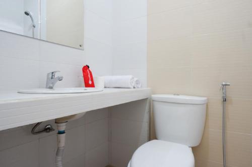 a white bathroom with a toilet and a sink at RedDoorz near Mataram University in Mataram