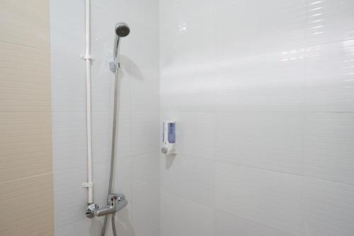 um chuveiro na casa de banho com azulejos brancos em RedDoorz near Mataram University em Mataram