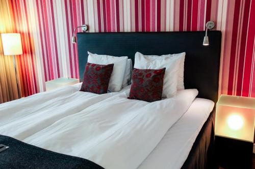 a white bed with two red pillows on it at First Hotel Witt in Kalmar