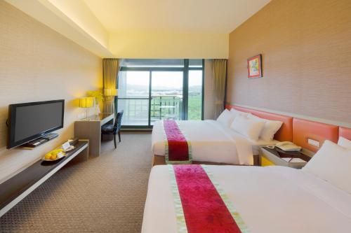 Formosan Naruwan Garden Hotel في مدينة تايتونج: غرفة فندقية بسريرين وتلفزيون بشاشة مسطحة